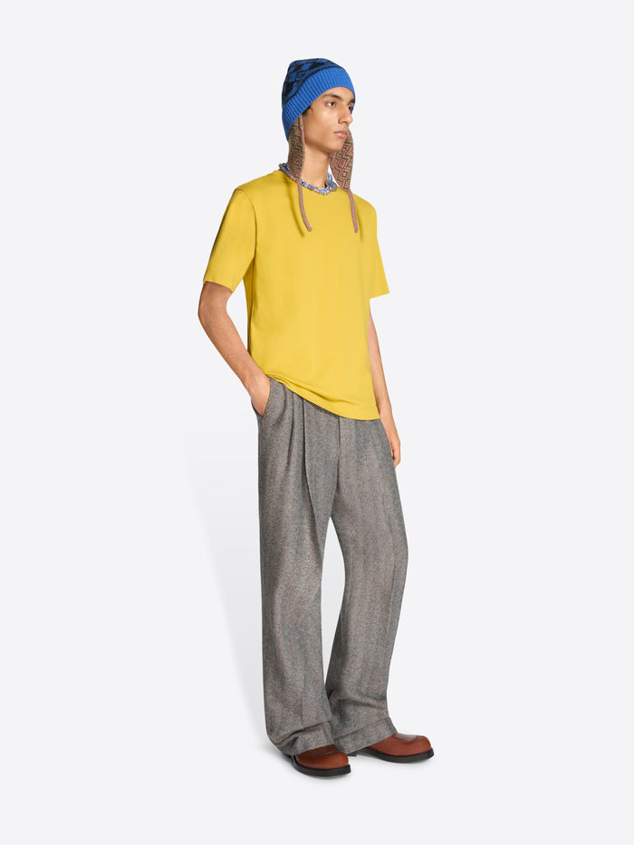Person wearing a yellow t-shirt, gray pants, and a blue hat on a white background