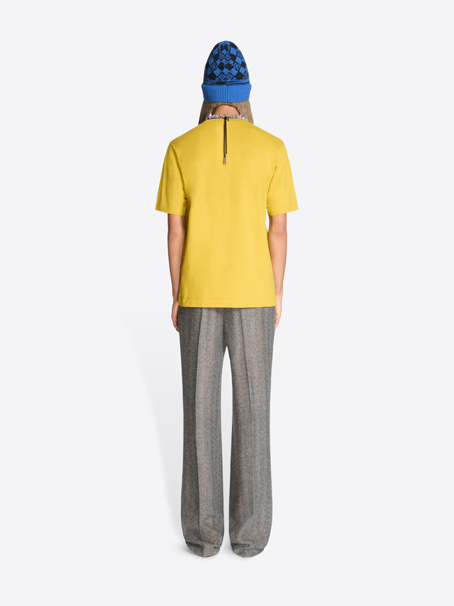 Back view of a person wearing a yellow t-shirt and gray pants with a blue hat on a white background