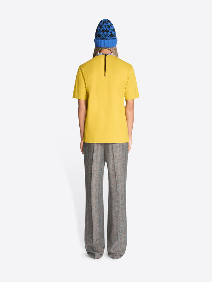 Back view of a person wearing a yellow t-shirt and gray pants with a blue hat on a white background