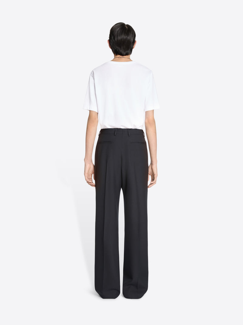 Back view of a person wearing a white shirt and navy pants on a white background