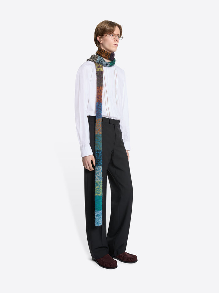 Person wearing a white shirt, black pants, and a colorful scarf on a white background