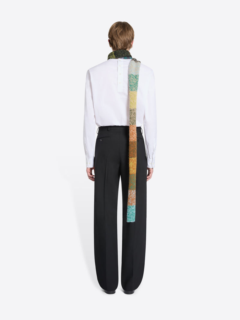 Back view of a person wearing a white shirt, black pants, and a colorful scarf on a white background