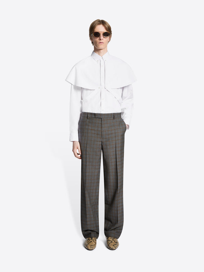 Person wearing a white blouse and brown checkered pants on a white background