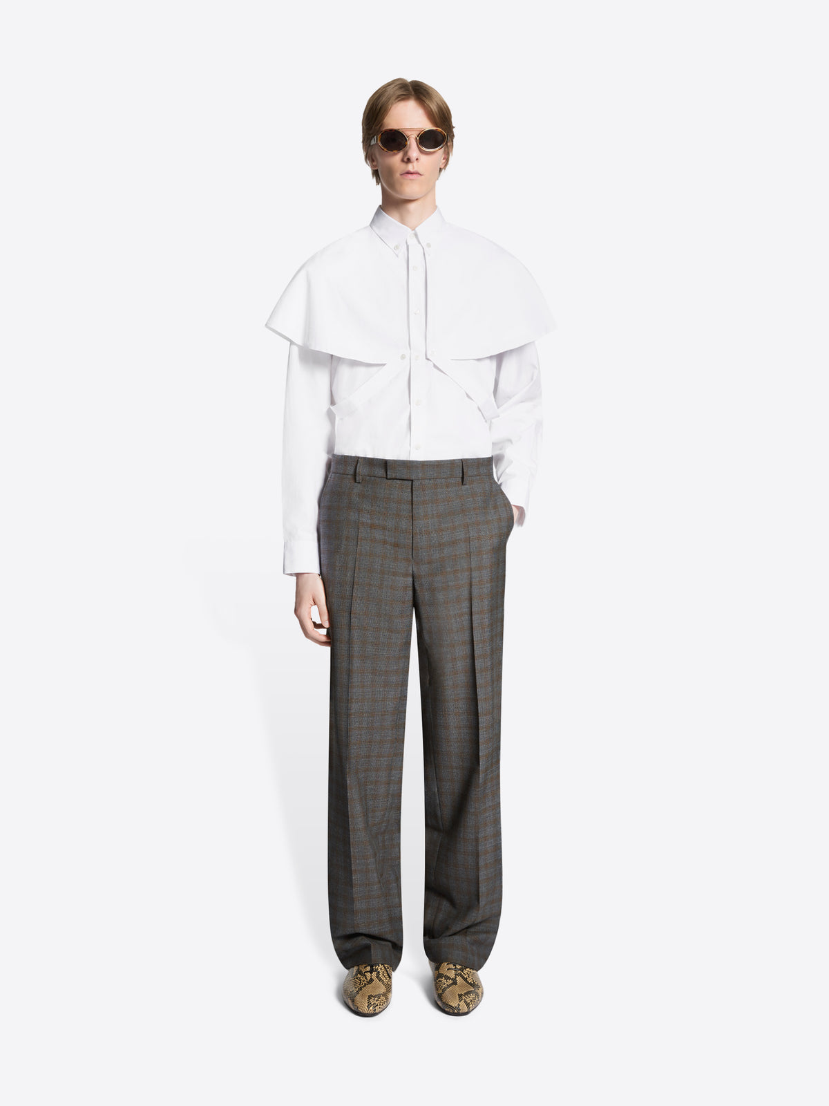 Person wearing a white blouse and brown checkered pants on a white background