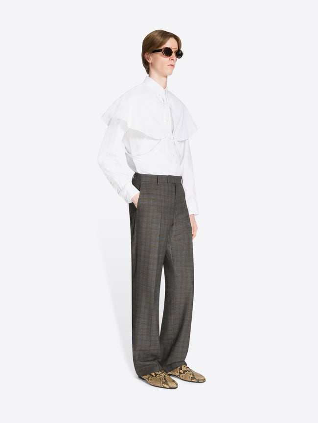 Person wearing a white shirt and brown checkered pants on a white background