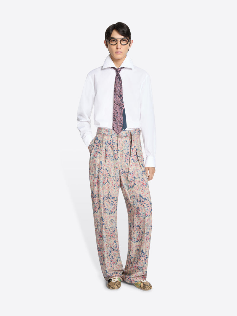 Person wearing a white shirt, patterned tie, and floral pants on a white background