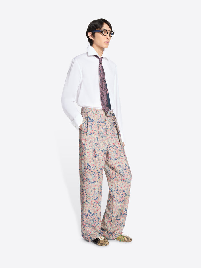 Person wearing a white shirt, patterned tie, and floral pants on a white background