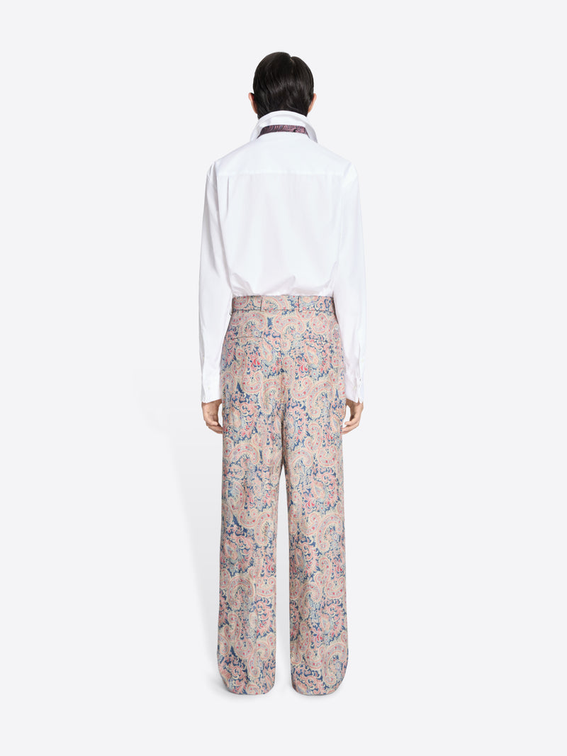 Back view of a person wearing a white shirt and floral pants on a white background