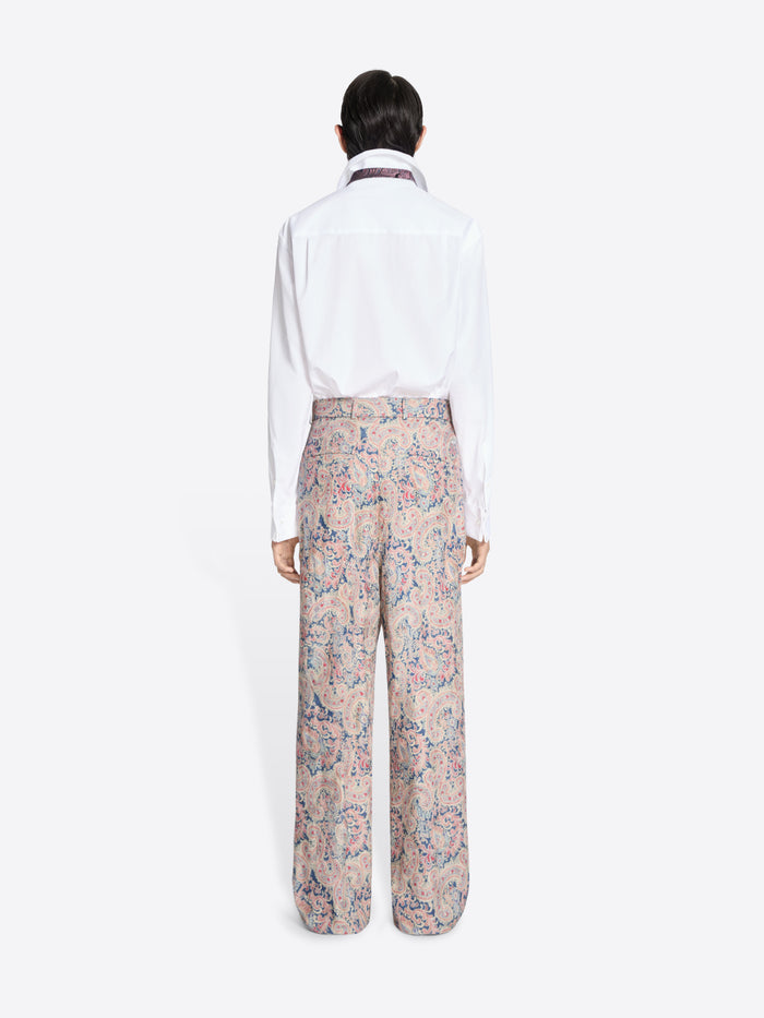 Back view of a person wearing a white shirt and floral pants on a white background