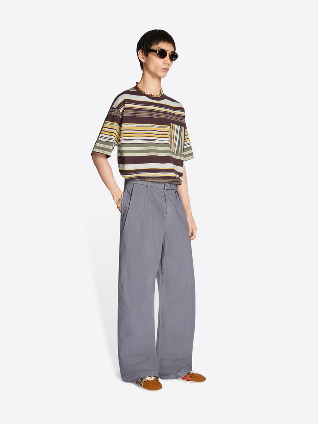 Person wearing a striped t-shirt and pleated gray pants on a white background