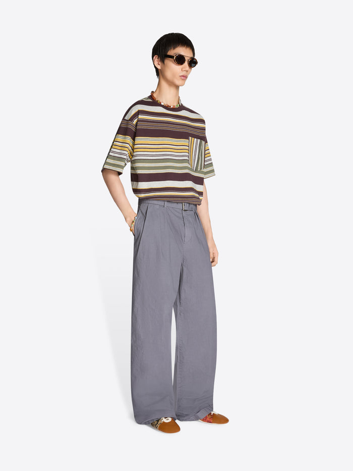 Person wearing a striped t-shirt and pleated gray pants on a white background