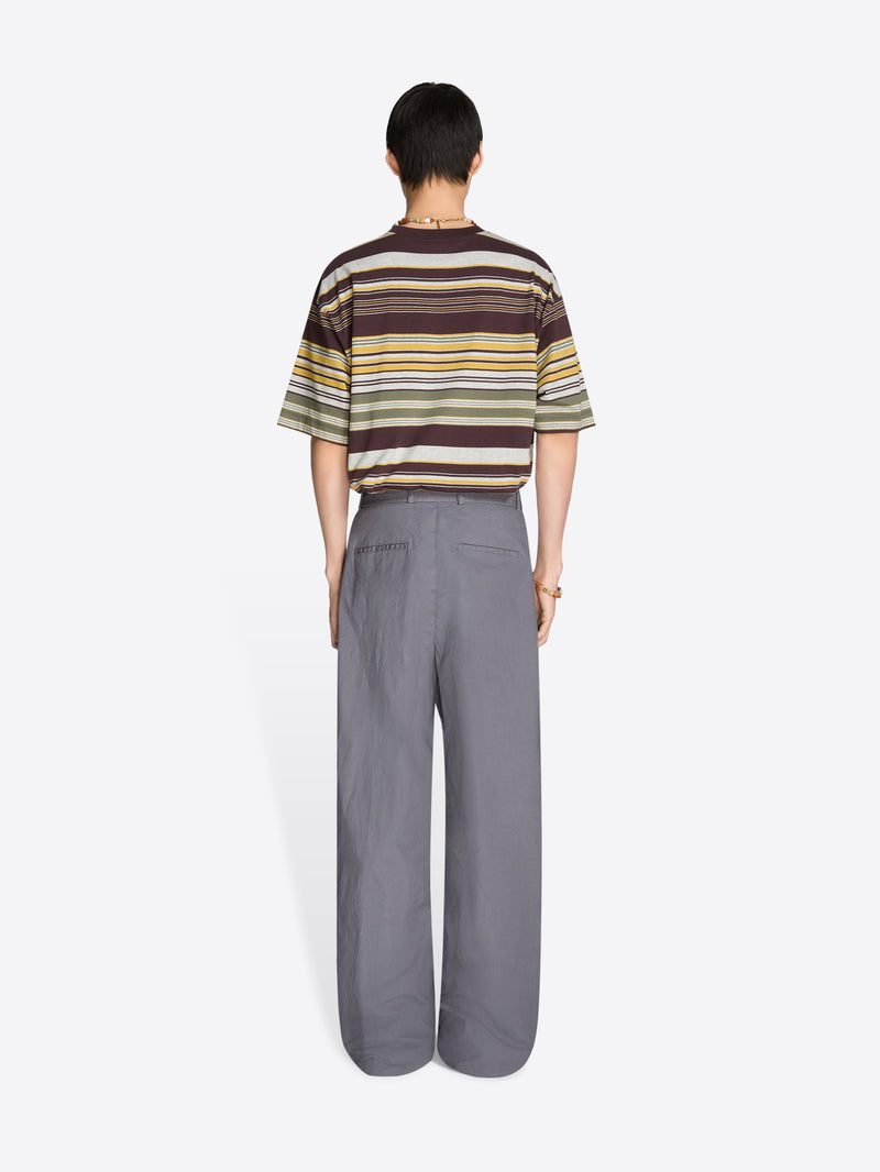 Back view of a person wearing a striped t-shirt and gray pants on a white background