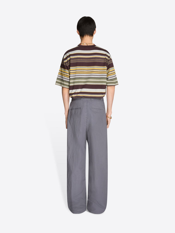 Back view of a person wearing a striped t-shirt and gray pants on a white background