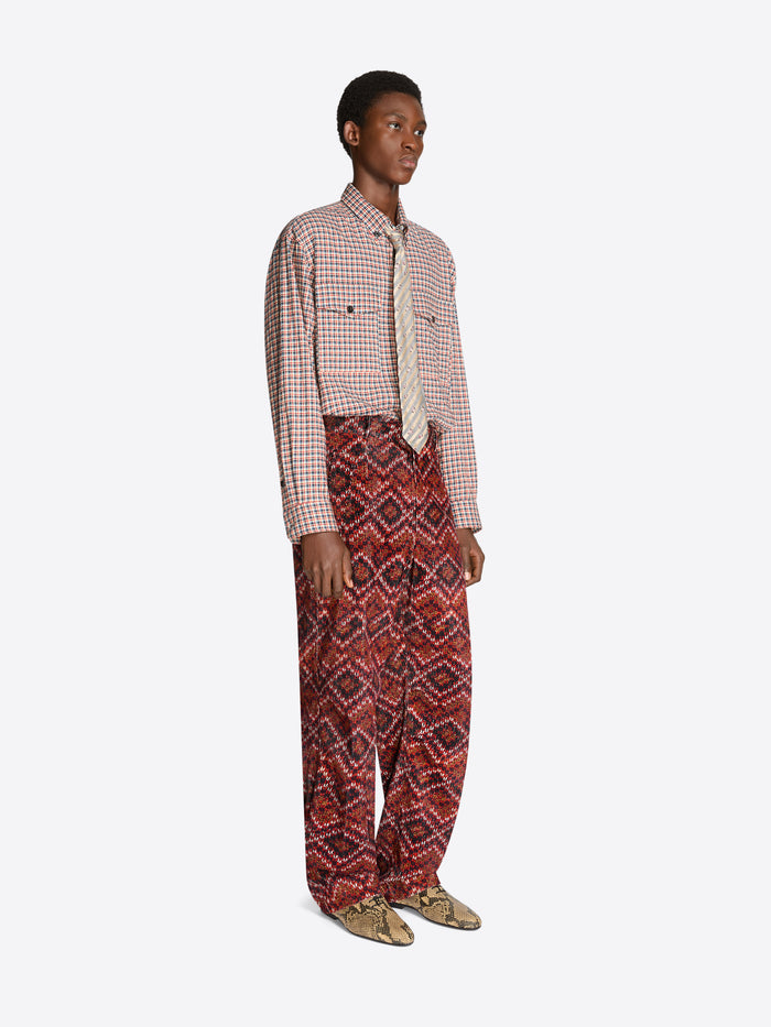 Person wearing a checkered shirt and patterned pants on a white background