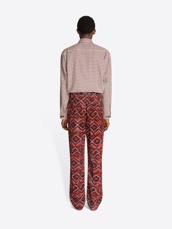 Person wearing a checkered shirt and patterned pants on a white background