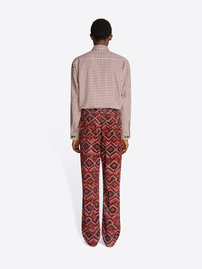 Person wearing a checkered shirt and patterned pants on a white background