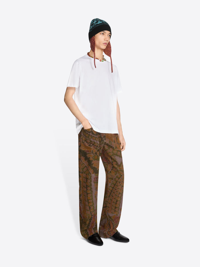 Person wearing a white t-shirt, patterned pants, and a hat on a white background