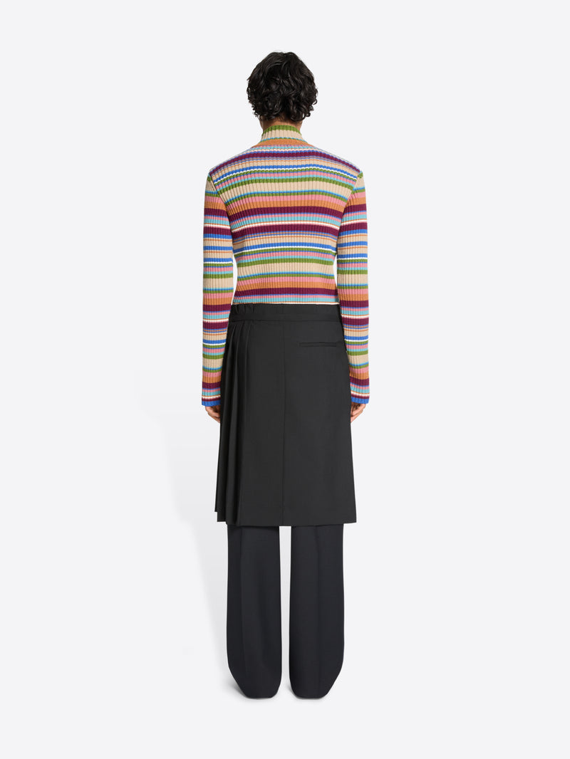 Person wearing a colorful striped sweater, black pants and black skirt on a white background