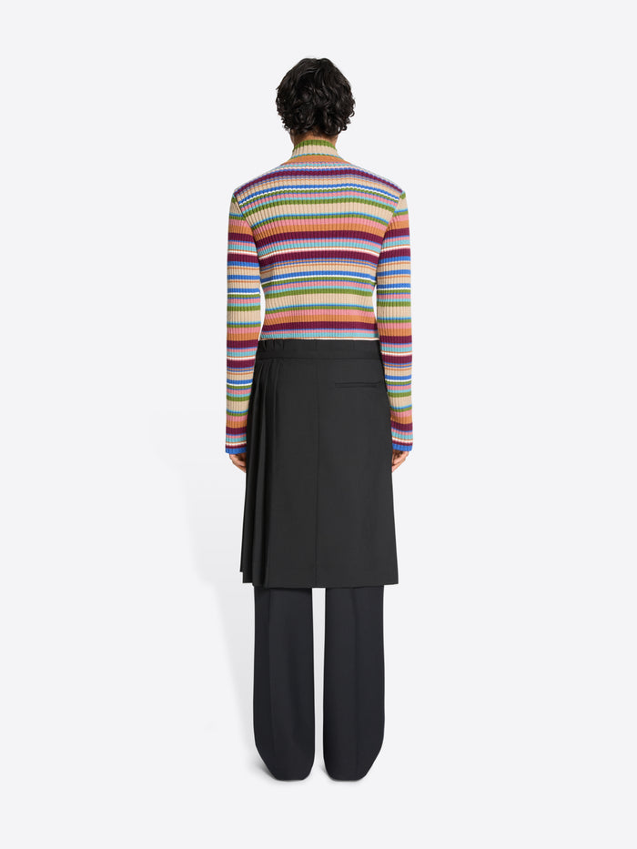 Person wearing a colorful striped sweater, black pants and black skirt on a white background