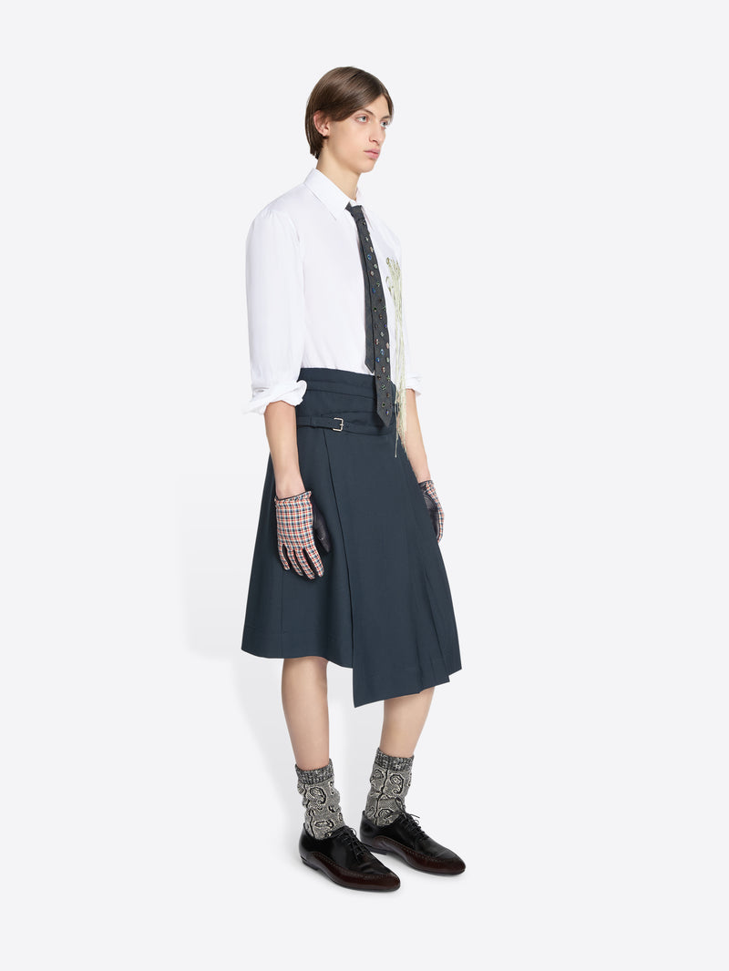 Person wearing a white shirt, dark skirt, patterned socks on a white background