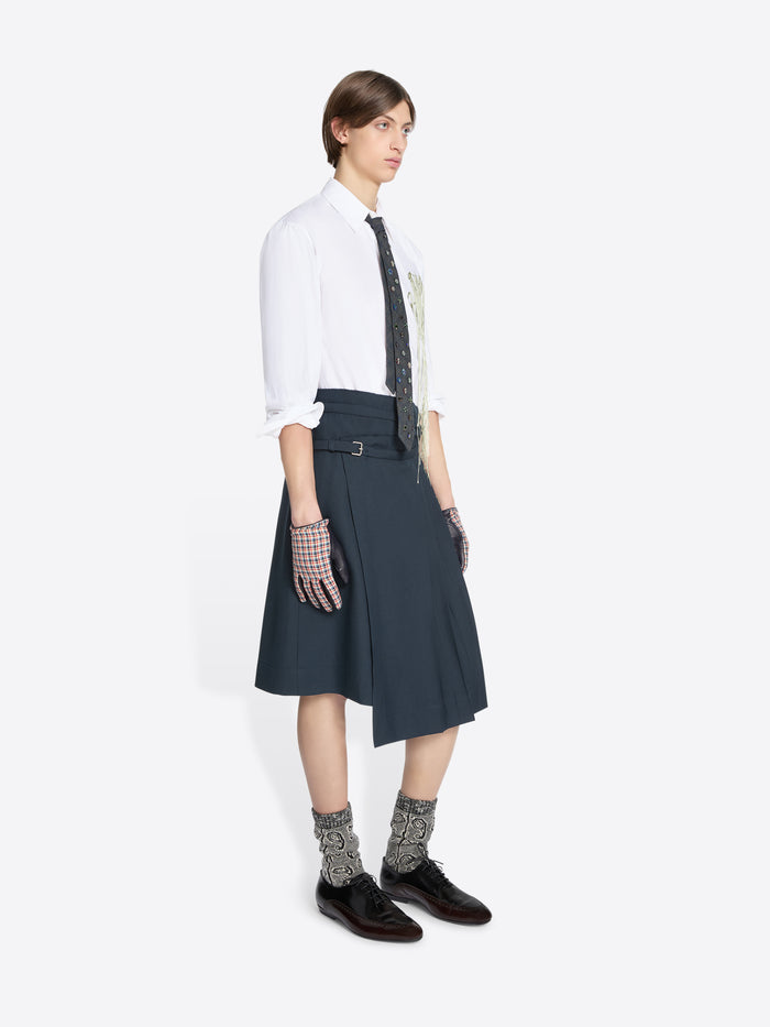 Person wearing a white shirt, dark skirt, patterned socks on a white background