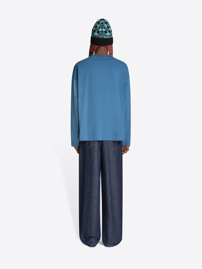 Back view of a person wearing a blue sweatshirt and dark jeans on a white background