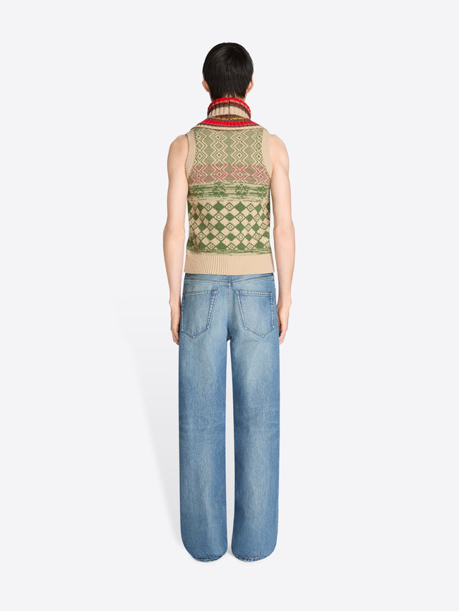 Back view of a person wearing a patterned sleeveless vest and blue jeans on a white background