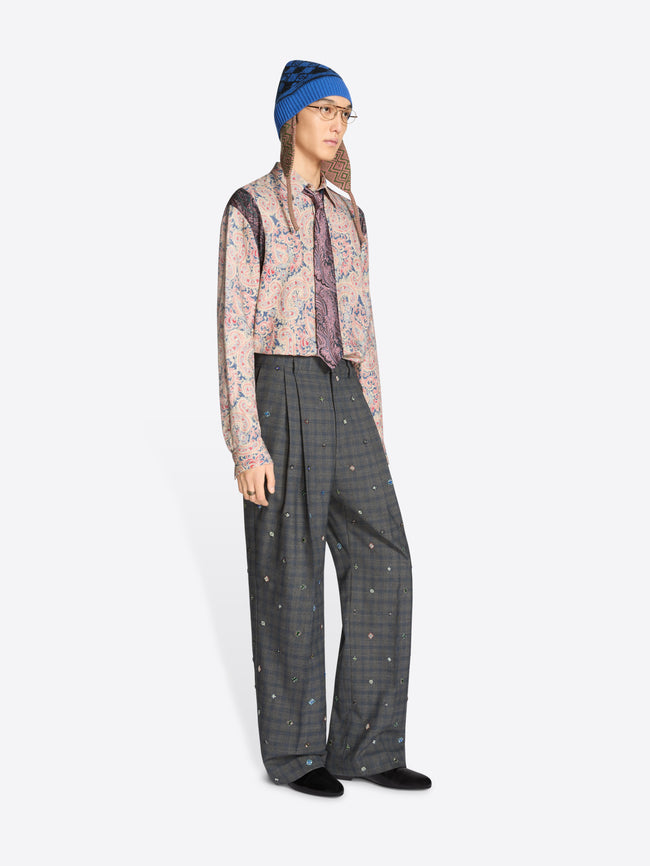 Person wearing a blue hat, patterned shirt, and gray checkered pants on a white background