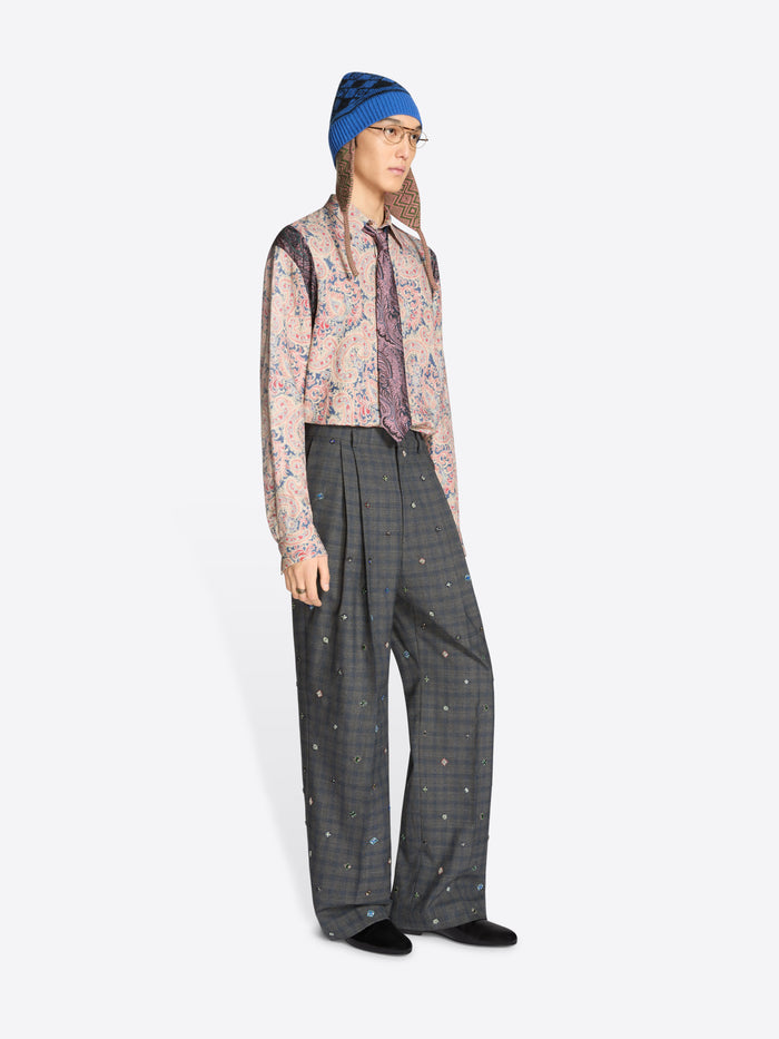 Person wearing a blue hat, patterned shirt, and gray checkered pants on a white background