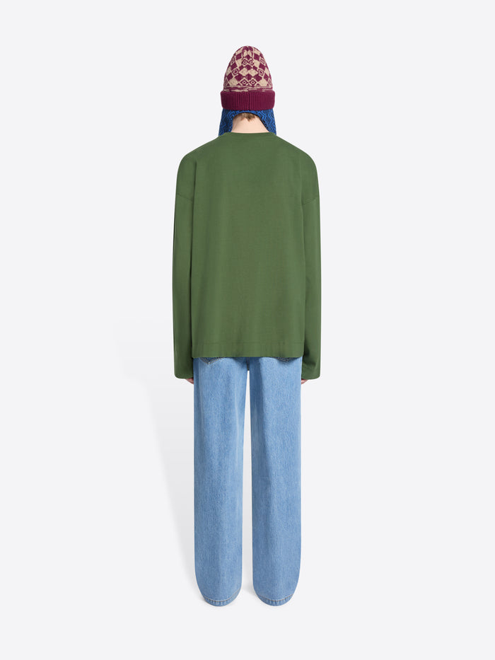 Back view of a person wearing a green sweatshirt and blue light jeans with a patterned beanie on a white background