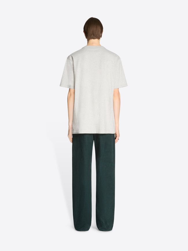 Back view of a person wearing a white t-shirt and dark green pants on a white background