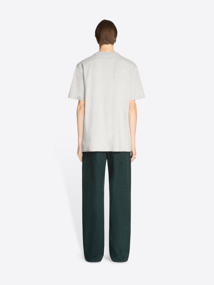 Back view of a person wearing a white t-shirt and dark green pants on a white background