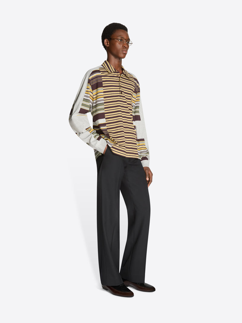 Person wearing a striped polo and black pants on a white background