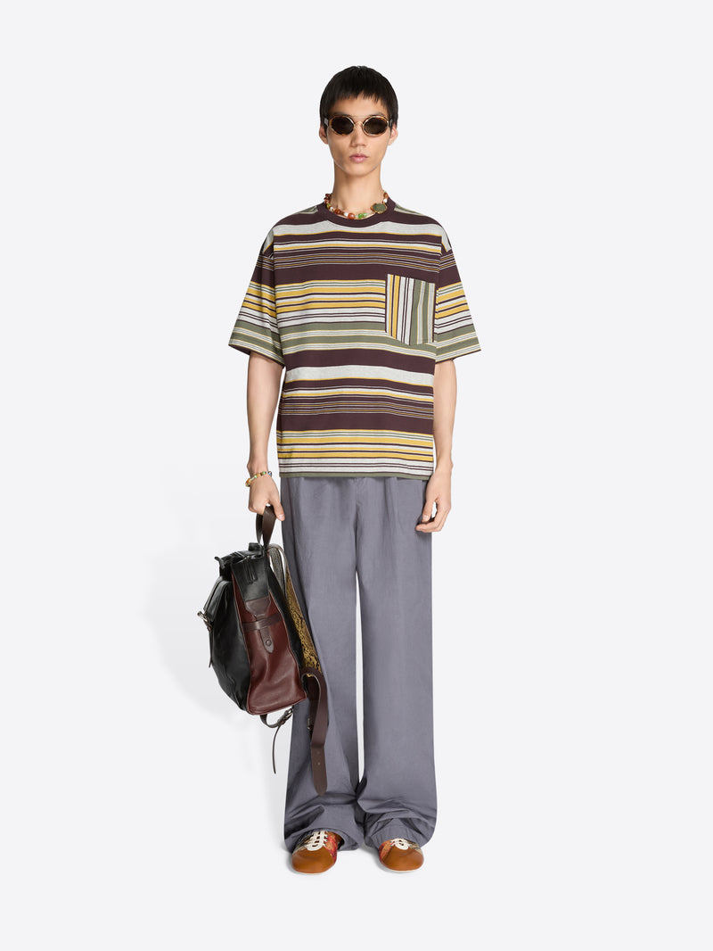 Person wearing a striped t-shirt and gray pants holding a backpack on a white background