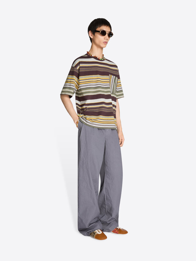 Person wearing a striped t-shirt and gray pants on a white background