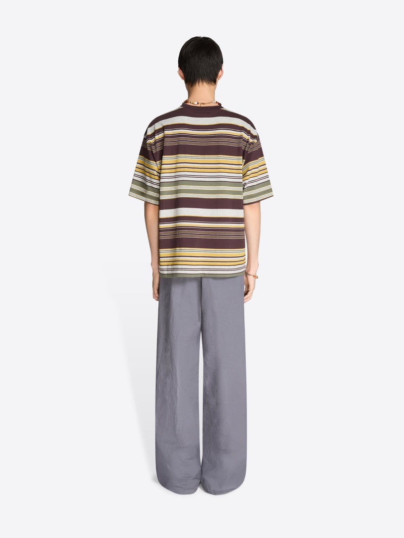 Back view of a person wearing a striped t-shirt and wide-leg pants on a white background