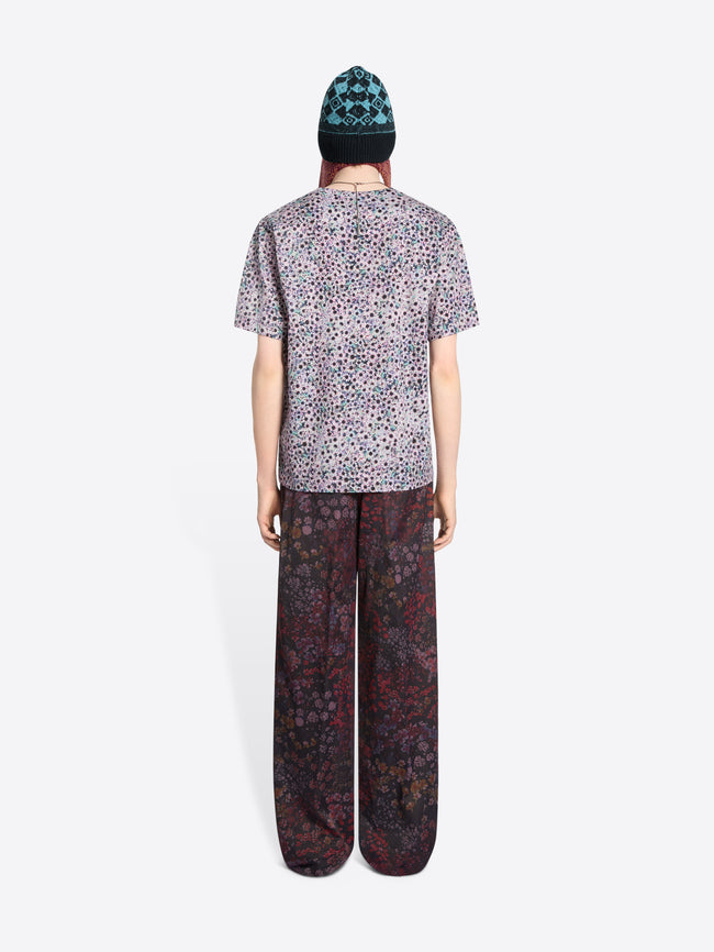 Person wearing a patterned t-shirt and pants with a bag on a white background