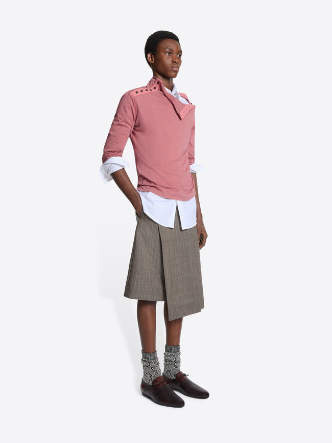 Person wearing a pink turtleneck tee, white shirt, pleated skirt, and shoes on a white background