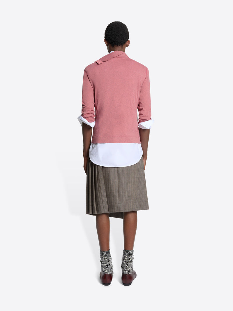 Back view of a person wearing a turtleneck tee, white shirt, and plaid skirt on a white background