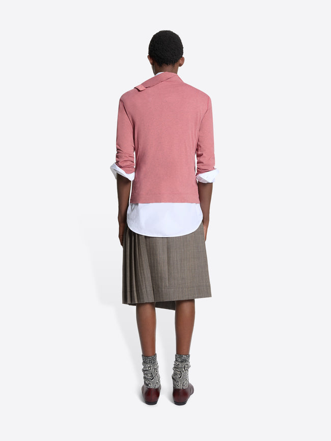 Back view of a person wearing a turtleneck tee, white shirt, and plaid skirt on a white background