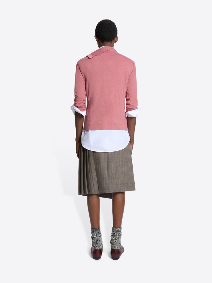 Back view of a person wearing a turtleneck tee, white shirt, and plaid skirt on a white background