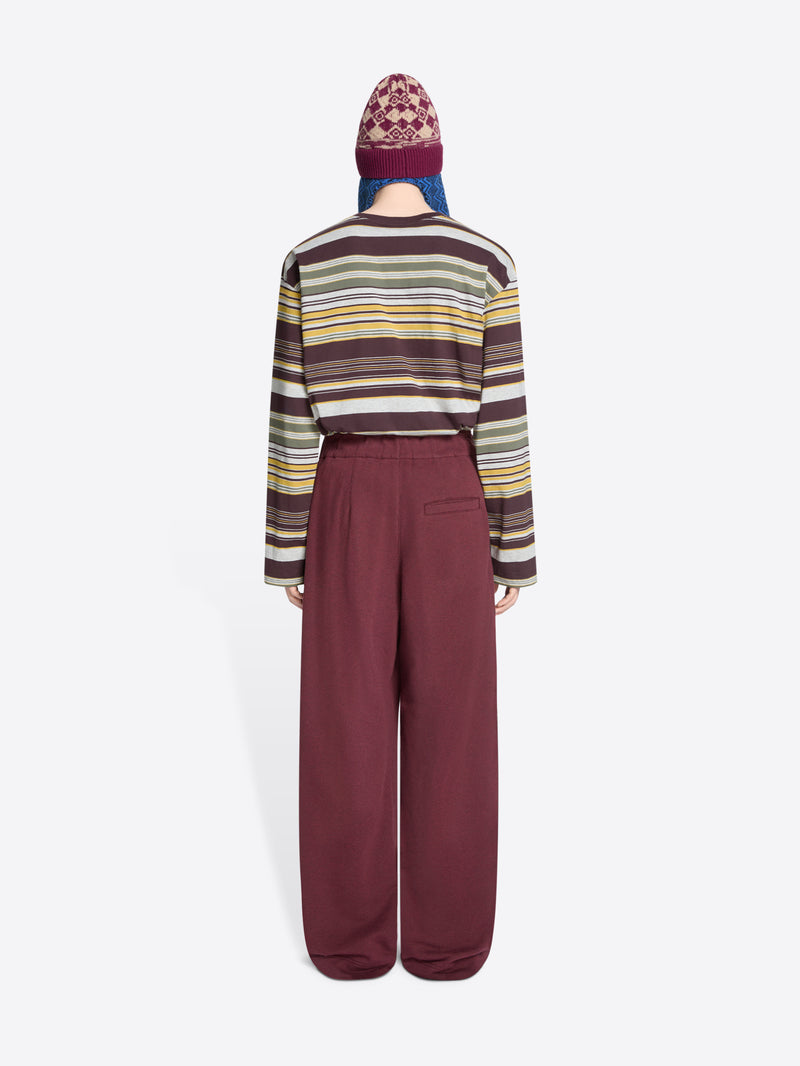 Back view of a person wearing a striped sweater, hat and wide-leg pants on a white background
