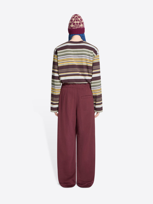 Back view of a person wearing a striped sweater, hat and wide-leg pants on a white background