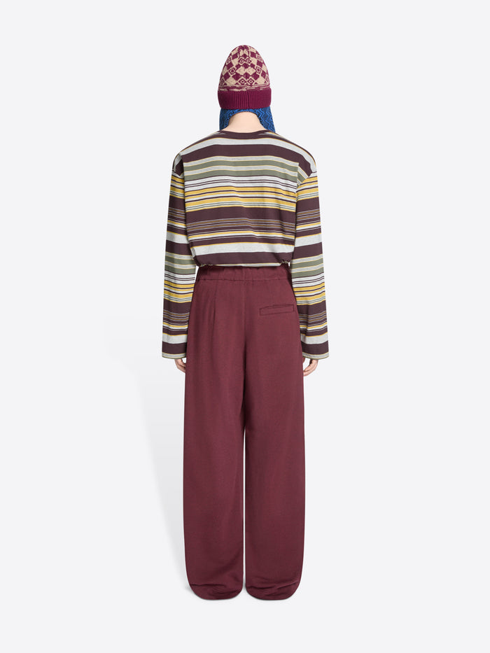 Back view of a person wearing a striped sweater, hat and wide-leg pants on a white background