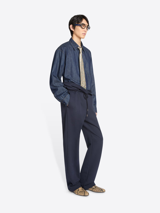 Person wearing a blue denim shirt and navy blue pants