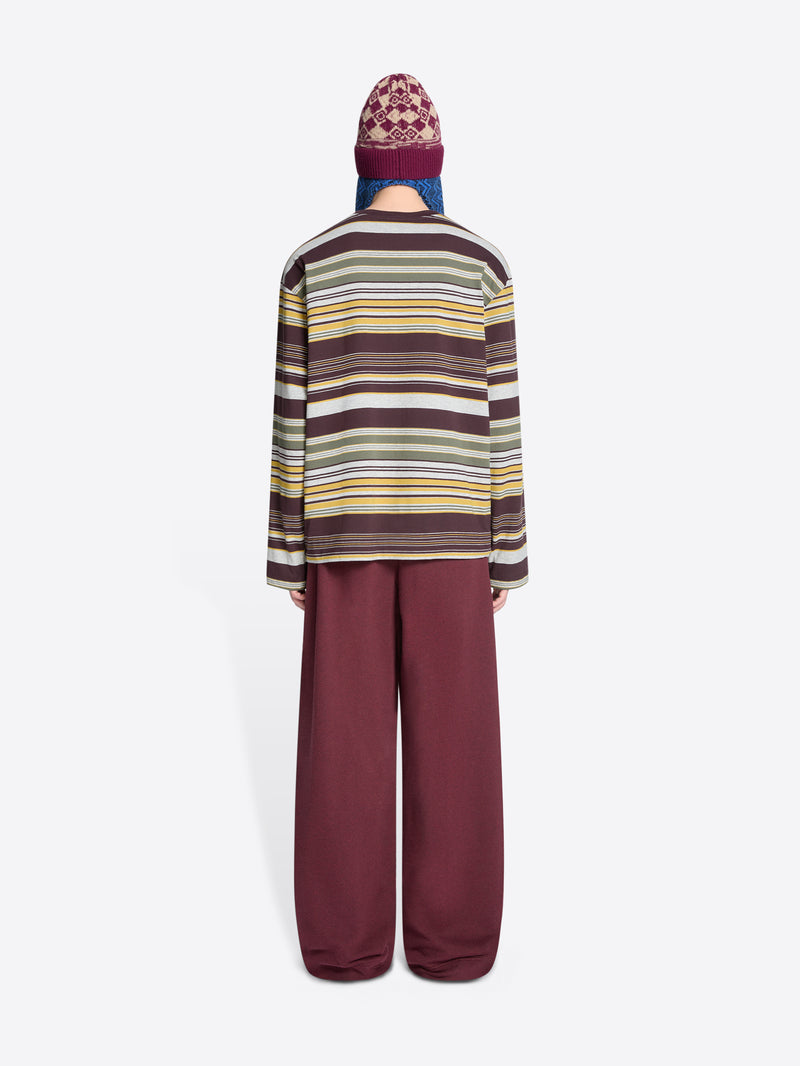 Back view of a person wearing a striped long-sleeve and burgundy pants with a patterned hat on a white background
