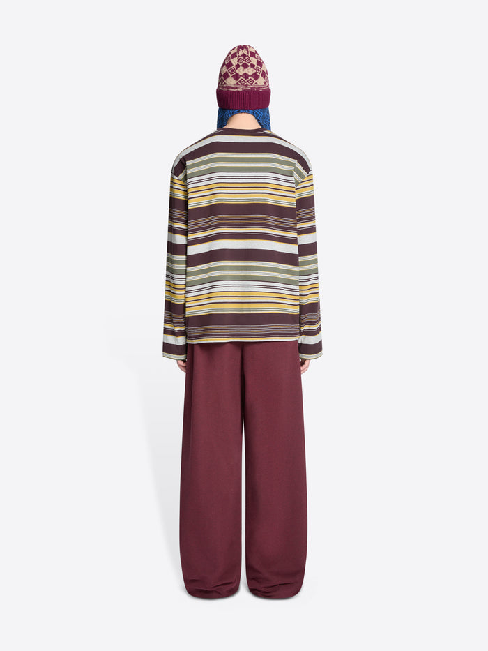 Back view of a person wearing a striped long-sleeve and burgundy pants with a patterned hat on a white background
