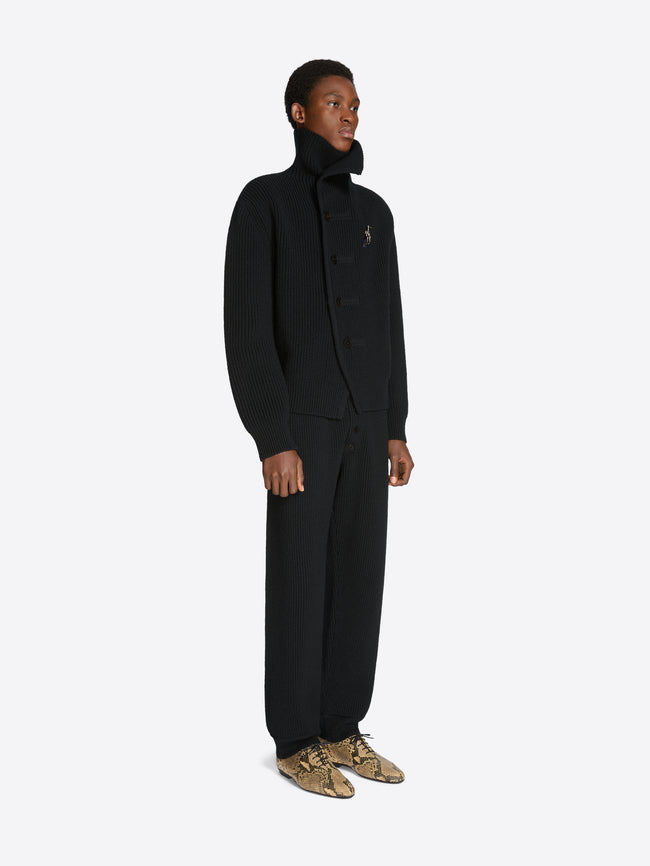 Man wearing a black ribbed knit cardigan and matching pants with a white background