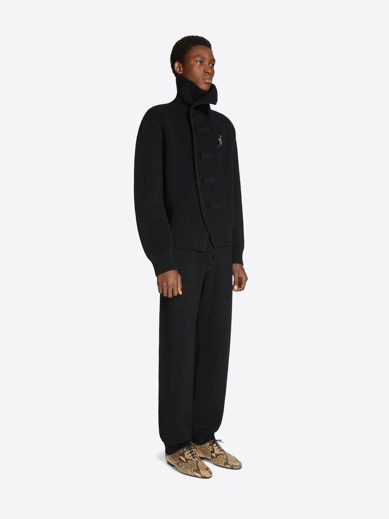 Person wearing a black set with coat and pants on a white background