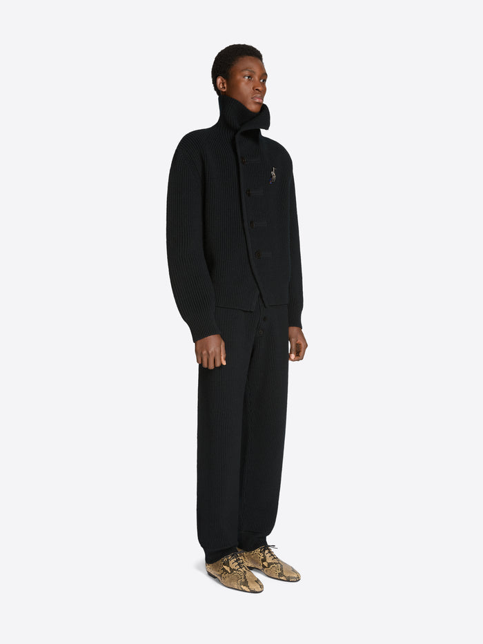 Person wearing a black set with coat and pants on a white background